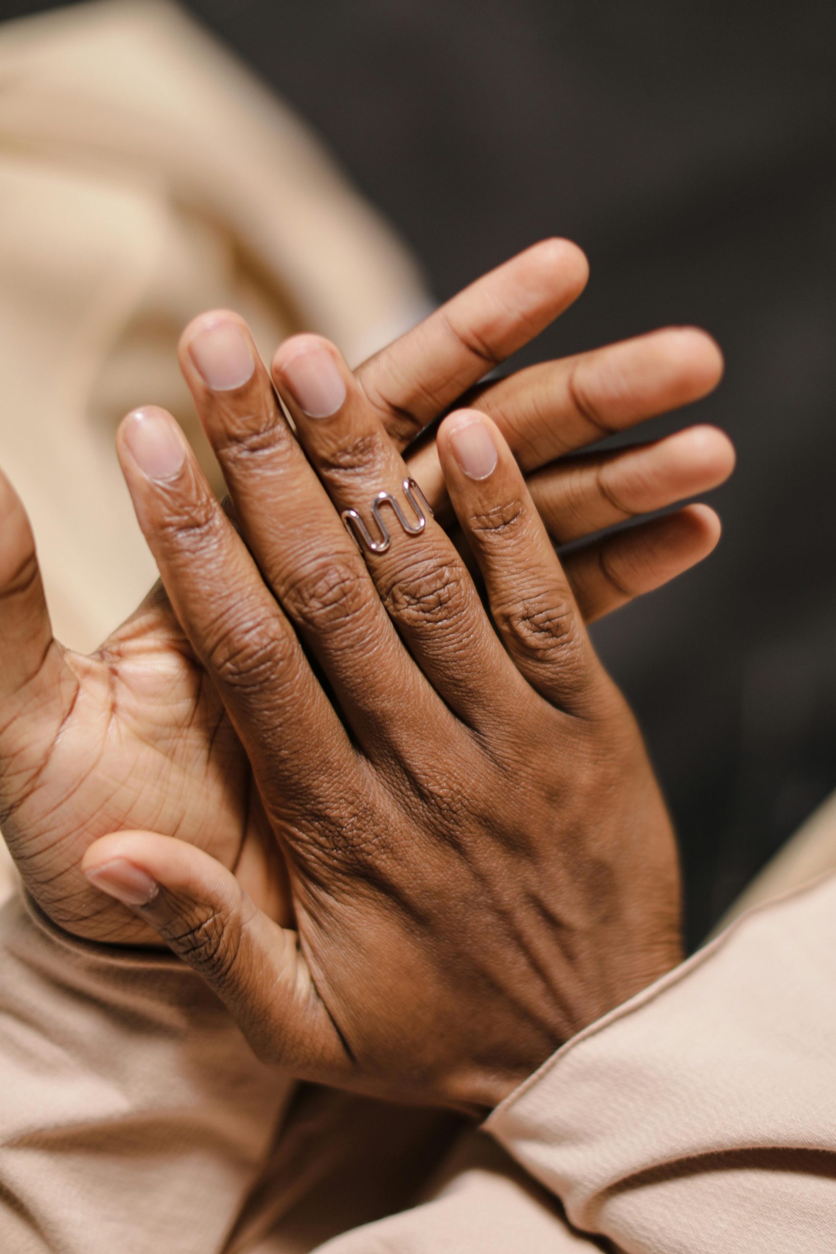 Close-up of human hands with a unique artistic ring, capturing elegant details and texture.